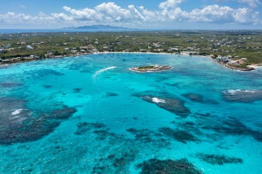 Ada Limanı 'nın ön planda Scilly Cay yakınlarında sürat teknesi ve Anguilla Adası' ndaki Saint Martin 'in hava görüntüsü..