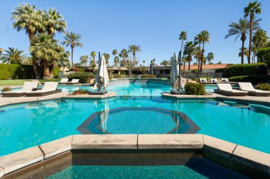 Indian Wells, CA 'de lüks bir mahallede şezlonglu sandalyeli büyük bir yüzme havuzu manzarası..