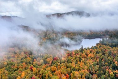 Connery Pond, New York, Adirondack Park 'taki Whiteface Dağı' nın yakınındaki sis ve bulutların arasından sonbaharda görülüyor..