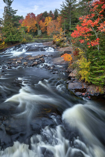 Водопад Бог-Ривер в парке Адирондак впадает в Большое озеро Таппер в разгар осени в северной части штата Нью-Йорк.