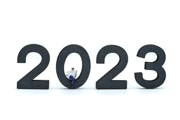 2023商业新年概念 商人们坐在那里 用白色背景的木制数字看报纸的小画像 — 图库照片