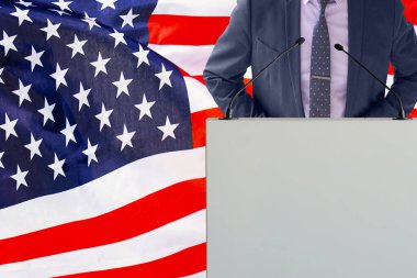 Mikrofonlu bir Tribün ve ABD bayraklarında takım elbiseli bir adam. İş adamı ve Tribün ABD bayrağı geçmişinde. Podyumdaki mikrofonlu politikacı Amerikan bayrağı. ABD 'de iş konferansı