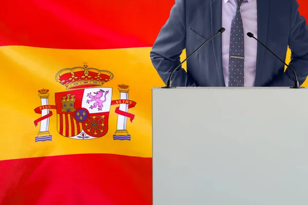 スペインの国旗を背景にマイクと男とのトリビューン ビジネスマンとスペインの旗の背景にトリビューン マイクを背景にした表彰台に立つ政治家スペイン国旗 ビジネス会議 — ストック写真