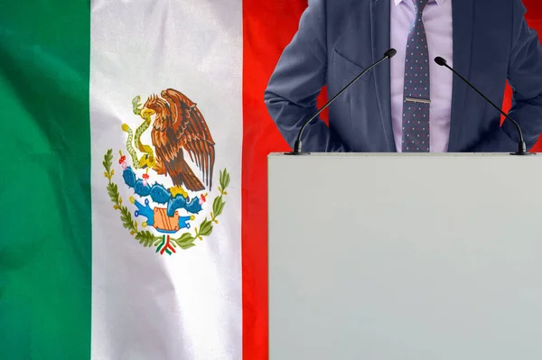 メキシコの国旗を背景にマイクと男とのトリビューン ビジネスマンとメキシコの旗の背景にトライブリーン マイクの背景メキシコの旗を持つ表彰台の政治家 — ストック写真