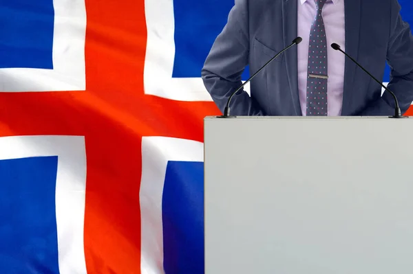 带着话筒和穿着西装的人在冰岛国旗背景上的论坛报 商人和部落在冰岛国旗背景上 领奖台上拿着麦克风的政客 背景是冰岛国旗 — 图库照片