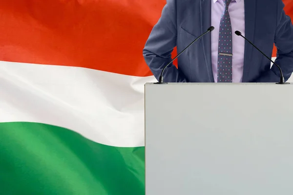 关于匈牙利国旗背景的带话筒和穿着西服的论坛报 在匈牙利国旗背景上的商人和部落客 领奖台上的政客 手持麦克风背景的匈牙利国旗 — 图库照片