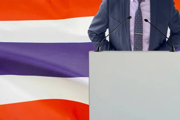 带着话筒和穿着西服的人在泰国国旗背景上的讲坛 在泰国国旗背景上的商人和领班 领奖台上的政客拿着麦克风背景的泰国国旗 — 图库照片