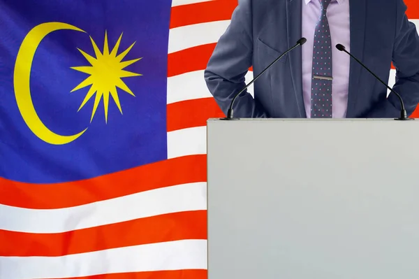 关于马来西亚国旗背景的带话筒和西服的论坛报 商人和部落在马来西亚国旗背景上 领奖台上的政客 手持麦克风背景的马来西亚国旗 — 图库照片