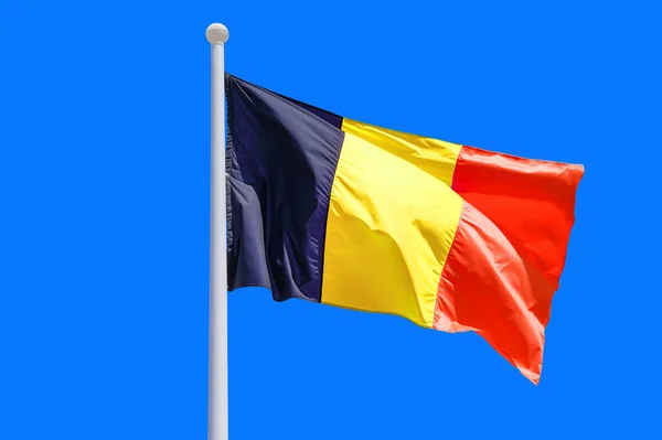 Belgium flag waving against clean blue sky, close up. Belgium flag in the blue sky. Flag Belgium on blue sky background