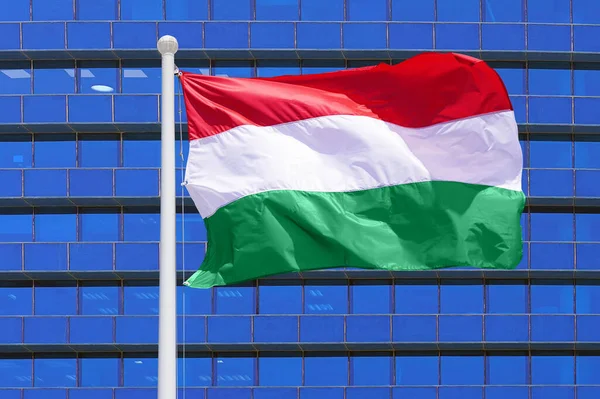 Wind Weht Die Ungarische Flagge Vor Dem Hintergrund Eines Modernen lizenzfreie Stockbilder