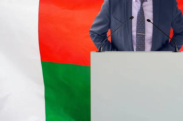 マダガスカルの国旗を背景にマイクと男とのトリビューン マダガスカルの旗の背景にビジネスマンと部族 マダガスカルの旗を背景にマイクと表彰台の政治家 — ストック写真