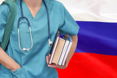 Steteskop ve Rusya bayrağı geçmişi ile ilgili kitapları olan yakın plan genç bayan doktor. Hemşire, öğrenci, eğitim. Üniversitede tıp öğrencisi. Rusya 'da tıp eğitimi