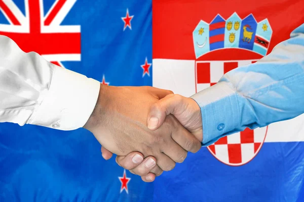 在两面旗帜的背景下进行商业握手 男子在新西兰和克罗地亚国旗的背景下握手 克罗地亚共和国的支助概念 — 图库照片