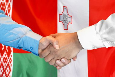 İki bayrağın arka planında iş tokalaşması. Beyaz Rusya bayrağı ve Malta bayrağı üzerinde erkekler el sıkışır. Destek konsepti