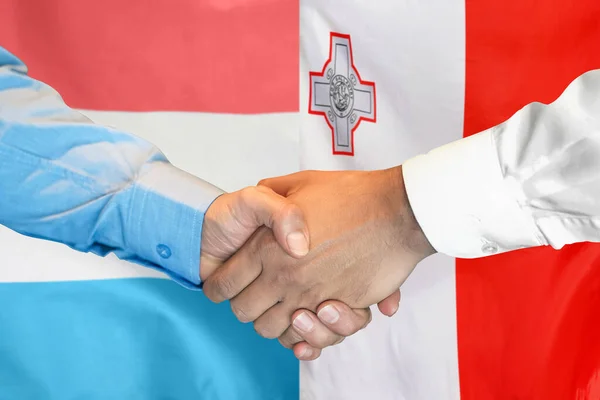 在两面旗帜的背景下进行商业握手 男子在卢森堡国旗和马耳他国旗的背景下握手 支助概念 — 图库照片