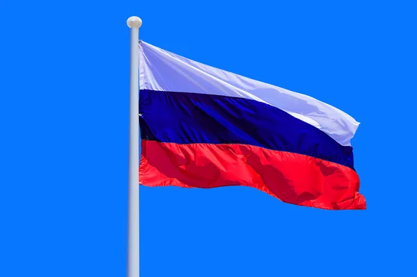Russia flag waving against clean blue sky, close up. Russia flag in the blue sky. Flag Russia on blue sky background