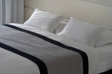 Yumuşak yastıklı bir otel odasında boş bir yatak. Turizm ve tatil kavramı