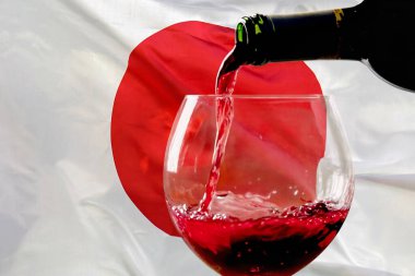 Japon bayrağının arka planında kırmızı şarap şişeden bardağa doluyor. Japonya 'da şarap ve şarap ihracatı kavramı