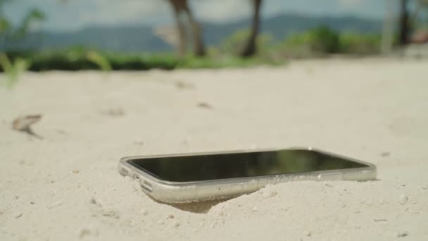 将智能手机关闭在沙滩度假胜地的沙滩上 背景是棕榈树 放弃移动设备或断开连接 以便在热带岛屿或岸上旅馆享受完全放松的假期或假期 — 图库视频影像