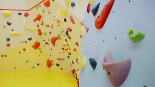 用各种彩色手柄紧紧抓住攀岩墙和卵石墙 攀爬或穿越攀爬中心或室内体育馆训练用的专业支架 把手或石子 — 图库视频影像