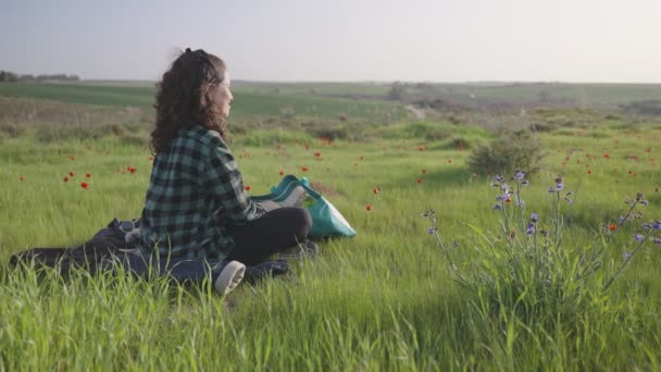 Молодая Женщина Наслаждается Свежим Воздухом Мирно Сидя Зеленом Поле Улыбаясь — стоковое видео