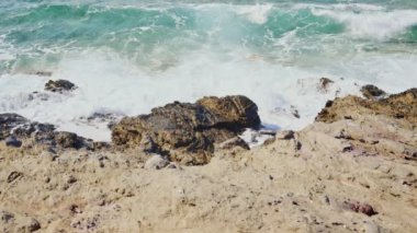 Yavaş çekim mavi ve turkuaz deniz dalgaları kayalıkların altında kırılıyor. Akdeniz 'deki taşlara güçlü akıntılar ve dalgalar vuruyor.