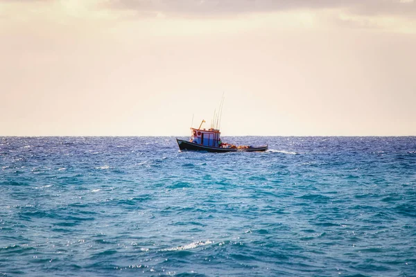 a small wooden fishing boat with cabin sails in the early morning in the open water on the Atlantic Ocean