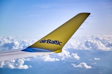 Uçakların kanat kanatları sarı. Mavi bulutlu gökyüzünün üzerinde Airbaltic logosu.