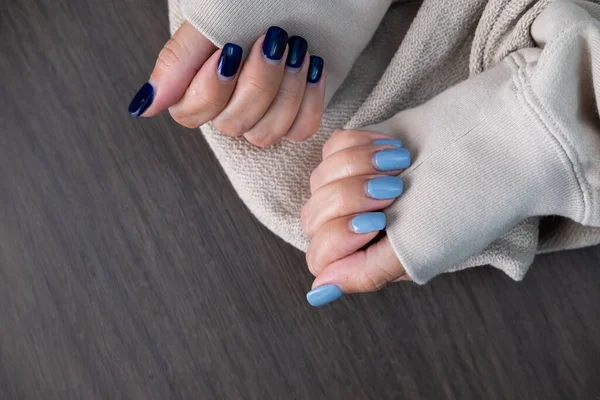Gel nail design.Beautiful manicure. Nail polish is applied to the hand, polish is a blue color. Blue background closeup. Multi-colored blue manicure.