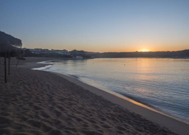 Mira nehri ve Forte de Milfonte kalesi ile Vila Nova de Milfontes 'teki boş kumsal Praia da Franquia' da turuncu gün doğumu. Portekiz, Rota Vicentina Sahili.
