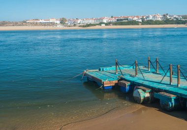 Praia das Furnas 'taki küçük turkuaz ahşap iskele Mira nehri üzerinden Vila Nova de Milfontes, Vicentine Coast Natural Park Portekiz manzaralı.
