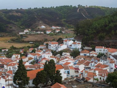 Rio Seixe nehri, yeşil tepeler ve otlayan ineklerin olduğu tarlalarla çevrili geleneksel köy Beyaz Saray 'ın üzerindeki hava manzarası. Alentejo, Portekiz