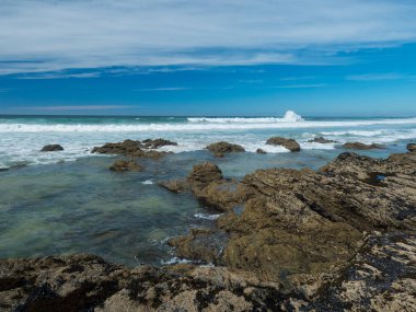 Portekiz, Porto Covo yakınlarındaki Rota Vicentina 'da okyanus dalgaları, keskin kayalar ve taşlarla deniz kıyısını görüntüle