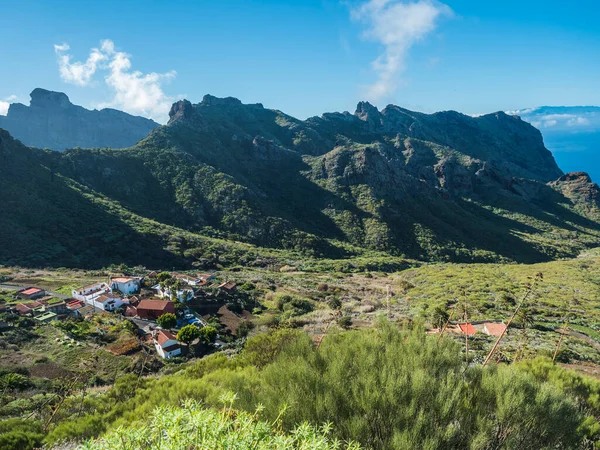 Dramatic lush green picturesque valley with old village Los Carrizales . Landscape with sharp rock formation, hills and cliffs seen from mountain road, Tenerife, Canary Islands, Spain. sunny winter