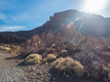Limestone rock formations and lava boulders at hiking trail to peak Alto de Guajara. Colorful dry volcanic scenic landscape at national park of Teide, Tenerife, Canary Islands. Lens flare, backlight.