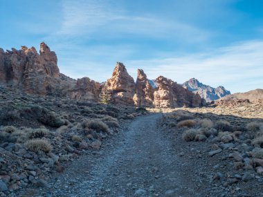 Limestone rock formations and lava boulders and dry vegetation at hiking trail to peak Alto de Guajara. Colorful dry volcanic scenic landscape at national park of Teide, Tenerife, Canary Islands