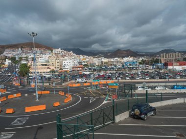 Los Cristianos, Tenerife, Canary Islands, Spain, december 26, 2021: Panoramic view of Los Cristianos from central parking at the port with city building, hotels, apartments and bare hills in distance.