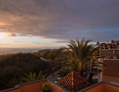 Vueltas 'ın Valle Gran Rey' deki hava manzarası, ana yol palmiye ağaçları, apartmanlar ve kumsaldaki Charco del Conde körfezi gün batımında. La Gomera, Kanarya Adaları, İspanya.