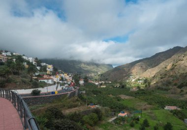 Hermigua, La Gomera, Kanarya Adaları, İspanya, 27 Aralık 2021: Hermigua köyünün renkli evleri yeşil vadide palmiye ağaçları ve teraslı tepeleri var..