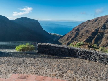 Mirador de la curva del queso 'dan hava görüntüsü. Valle Gran Rey 'in yeşil vadisi. Dağ kayalıkları, okyanus ve tarlaları olan renkli evler. La Gomera, Kanarya Adası, İspanya.