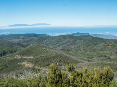 Garajonay Ulusal Parkı 'nın tepeleri ve defne ağacı ormanının üzerindeki La Palma adasında Garajonay Dağı' nın zirvesinden görülmektedir. Beyaz bulutlar ve mavi gökyüzü. La Gomera, Kanarya Adaları, İspanya