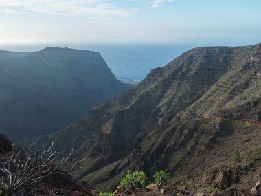 Vueltas köyü ve büyük kayalıkları olan vadideki La Merica dağının tepesindeki platodan manzara. Camino La Merica yürüyüş parkuru. Valle Gran Rey, La Gomera, Kanarya Adaları