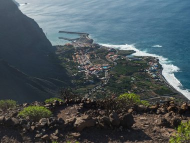 Limanı olan köy tatil beldesi Vueltas 'ın havadan görünüşü, La Merica dağ uçurumlarının tepesinden, Camino La Merica yürüyüş patikasından görülüyor. Valle Gran Rey, La Gomera, Kanarya Adaları. Boşluğu kopyala