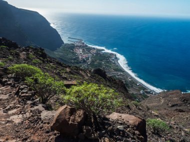 Limanı olan köy tatil beldesi Vueltas 'ın havadan görünüşü, La Merica dağ uçurumlarının tepesinden, Camino La Merica yürüyüş patikasından görülüyor. Valle Gran Rey, La Gomera, Kanarya Adaları. Boşluğu kopyala