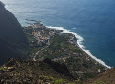 Limanı olan köy tatil beldesi Vueltas 'ın havadan görünüşü, La Merica dağ uçurumlarının tepesinden, Camino La Merica yürüyüş patikasından görülüyor. Valle Gran Rey, La Gomera, Kanarya Adaları. Boşluğu kopyala
