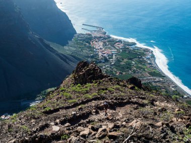 Limanı olan köy tatil beldesi Vueltas 'ın havadan görünüşü, La Merica dağ uçurumlarının tepesinden, Camino La Merica yürüyüş patikasından görülüyor. Valle Gran Rey, La Gomera, Kanarya Adaları. Boşluğu kopyala