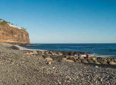 Playa de Santiago, La Gomera, Kanarya Adaları, İspanya. 1 Ocak 2022: Playa de Santiago, güneşli bir kış gününde turistlerle kara kum ve taş plajı.