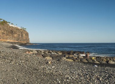 Playa de Santiago, La Gomera, Kanarya Adaları, İspanya. 1 Ocak 2022: Playa de Santiago, güneşli bir kış gününde turistlerle kara kum ve taş plajı.