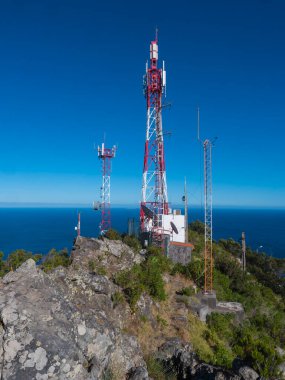 Telekomünikasyon kulesi antenleri ve mavi gökyüzü arka planıyla Pico do Facho Tepesi, Machico, Madeira, Portekiz.