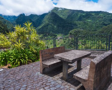 Yeşil tepeler ve vadi manzaralı beton tezgah ve masa. Sao Roque do Faial Santana, Madeira Adası, kuzey sahili manzaralı.